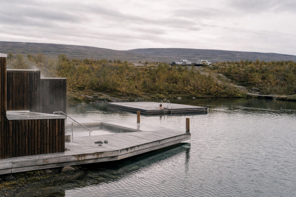 Floating wooden pools on a still lake surrounded by low hills