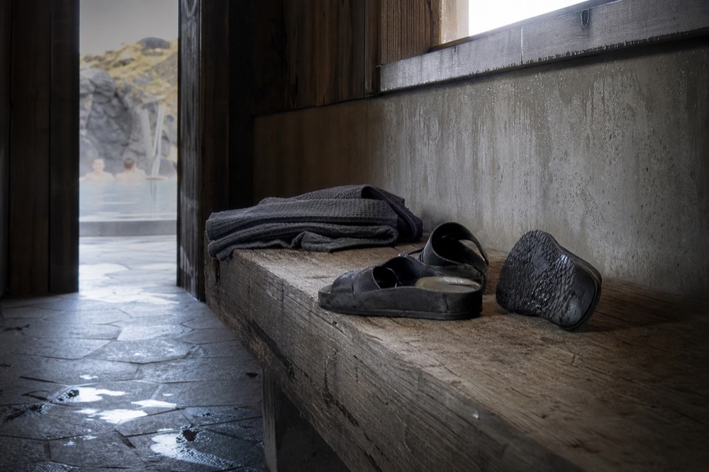 A pair of sandals resting on a bench beside a folded towel in a spa changing room