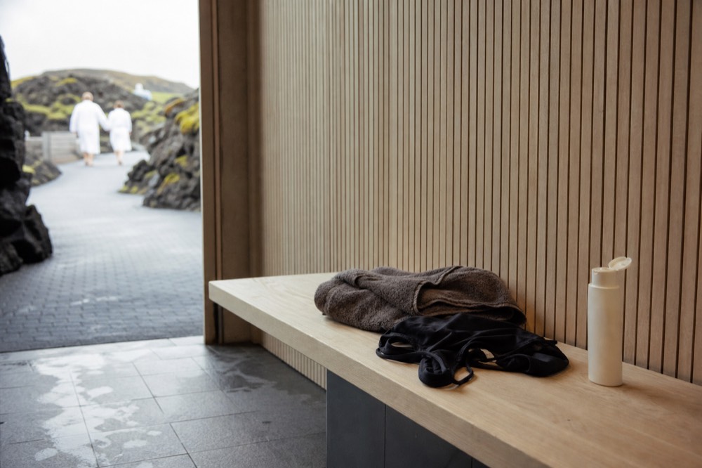 A folded towel and swimsuit on a wooden bench in a bright changing room