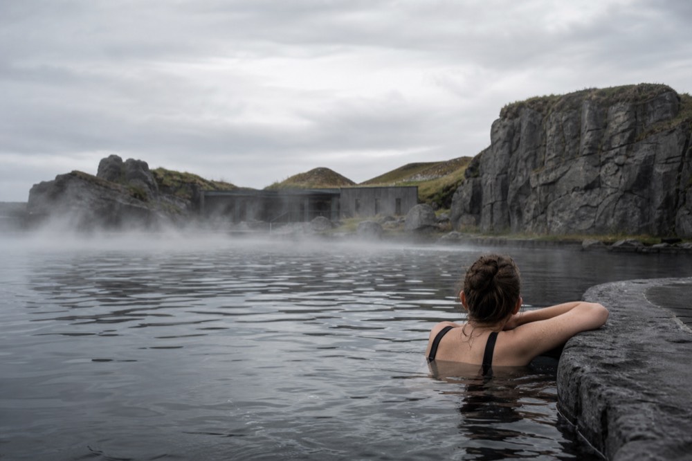 A swimmer resting arms on the edge of a lagoon looking toward the sea