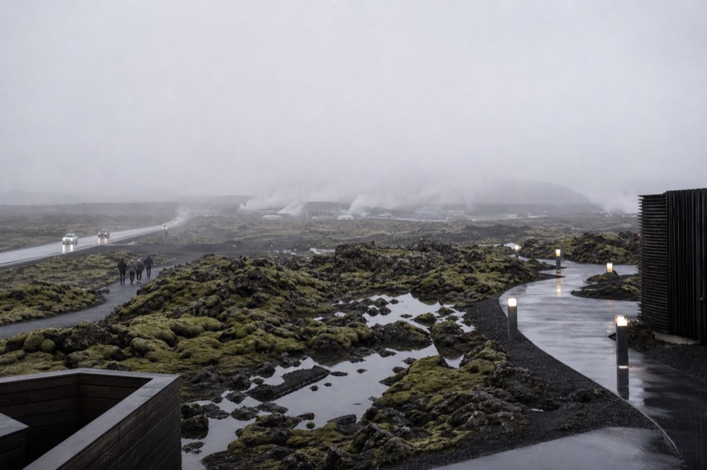 Misty morning over a coastal lava plain with a low ridge and a distant airport road