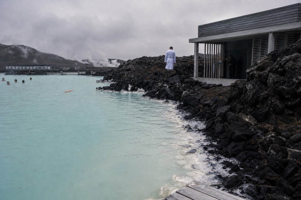 Pale turquoise geothermal lagoon water edged by dark lava rock