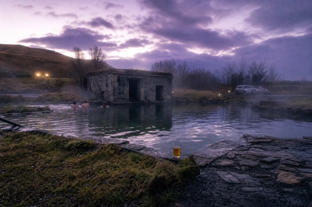 A historic geothermal pool at dusk with steam drifting across still water