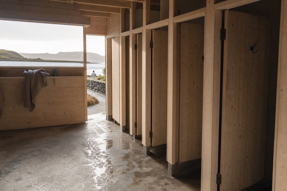 A row of shower cubicles with wooden doors inside a geothermal bathing facility