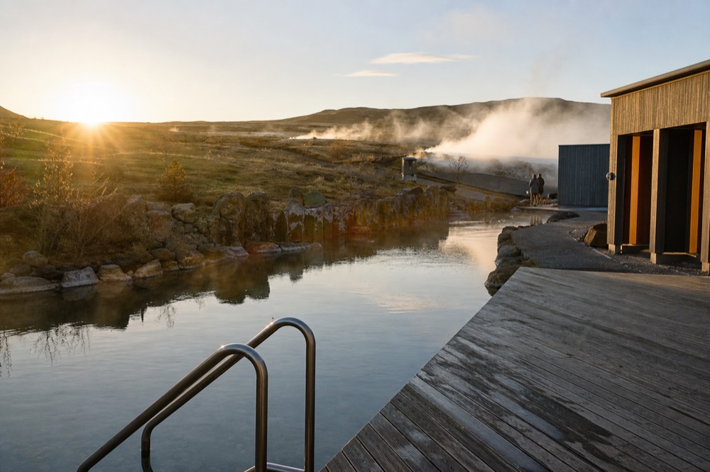 Still geothermal water reflecting a low sun beside a wooden deck