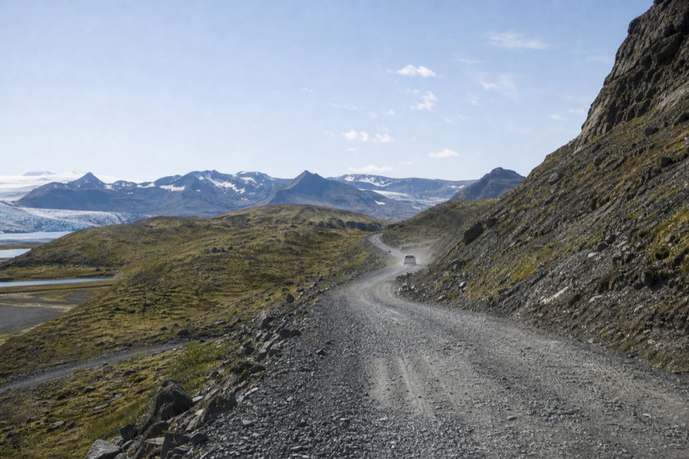 A winding gravel mountain road through rhyolite hills toward a highland valley