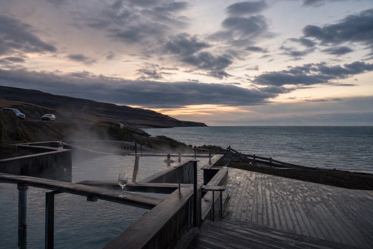 Steam rising from a geothermal lagoon at dusk with dark mountains behind