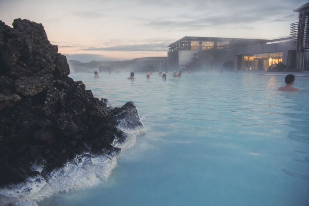 Geothermal lagoon with steam drifting across still water at dusk