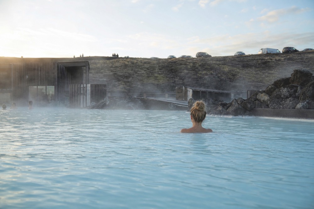 Long hair clipped up above the surface of a milky blue geothermal pool