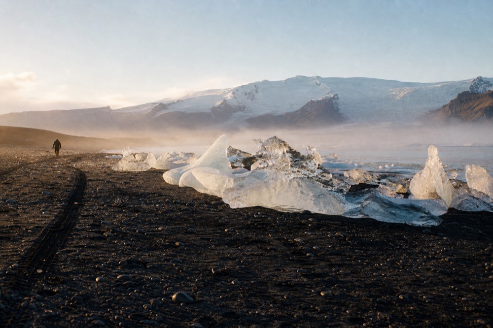 Icebergs grounded on black sand at the edge of a glacial lagoon in low light