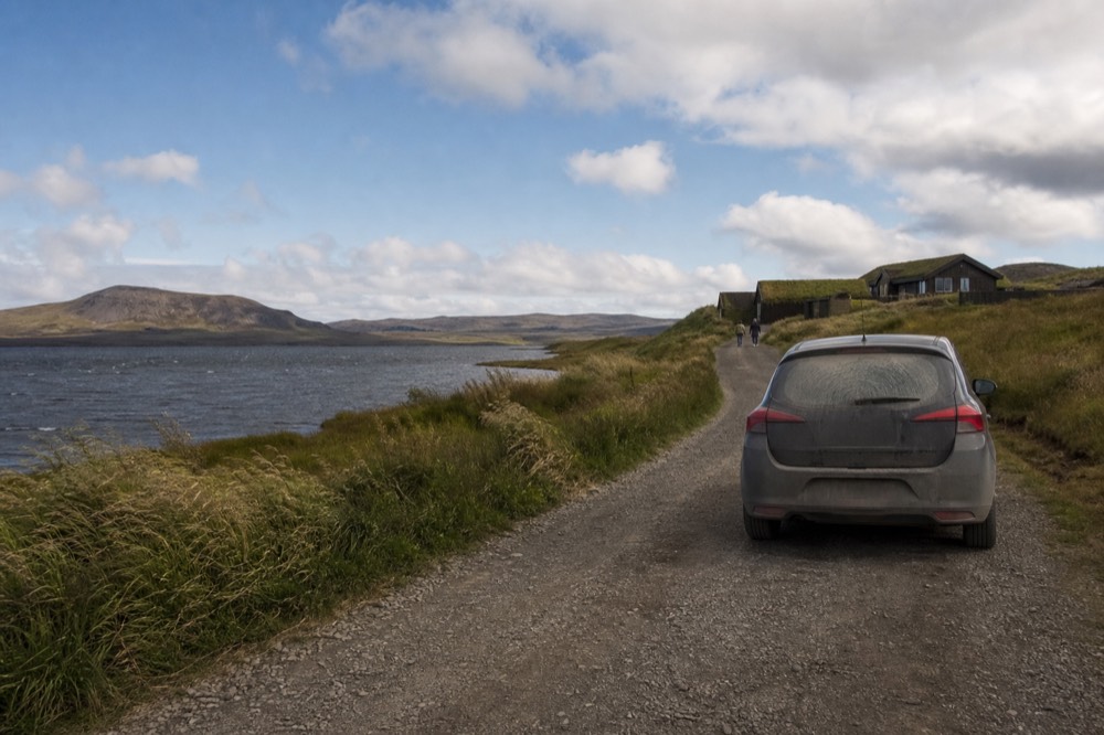 A quiet country road beside a lake with mountains in the distance