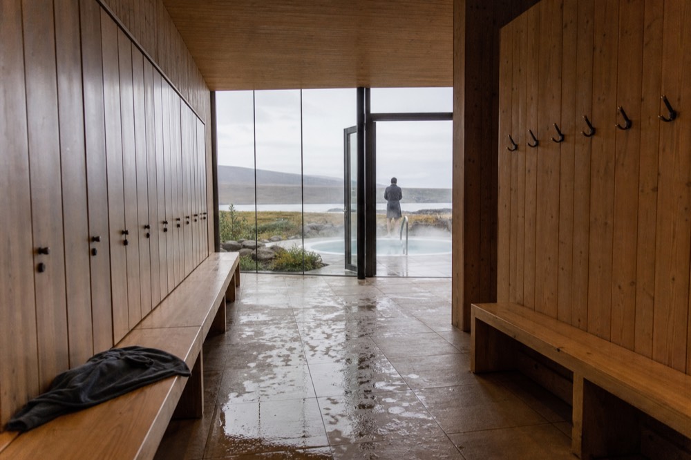 A row of wooden lockers in a bright changing room with tiled floor