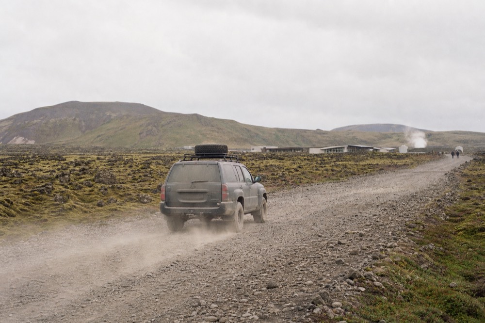 A four-wheel-drive vehicle on a gravel road crossing an open highland plain