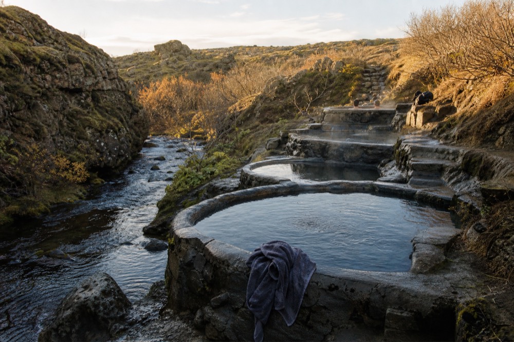 A row of wooden hot pools of different sizes built into a hillside