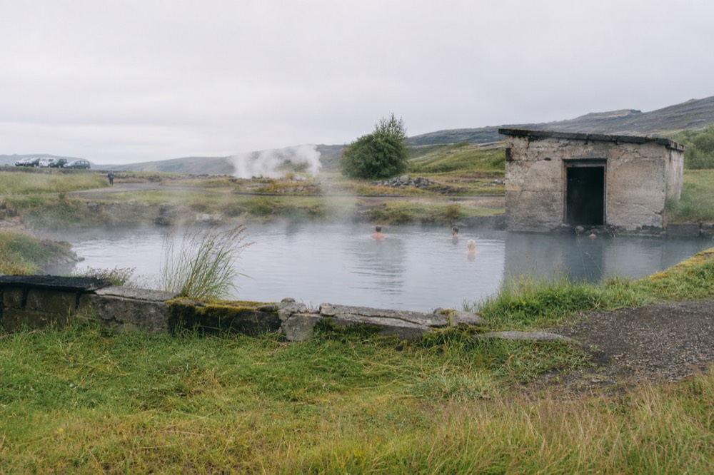 A modest geothermal pool with steam drifting across still water