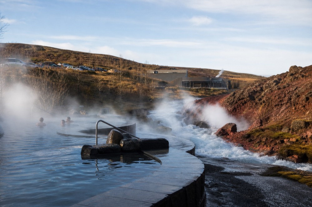 Terraced geothermal pools releasing steam beside a powerful hot spring
