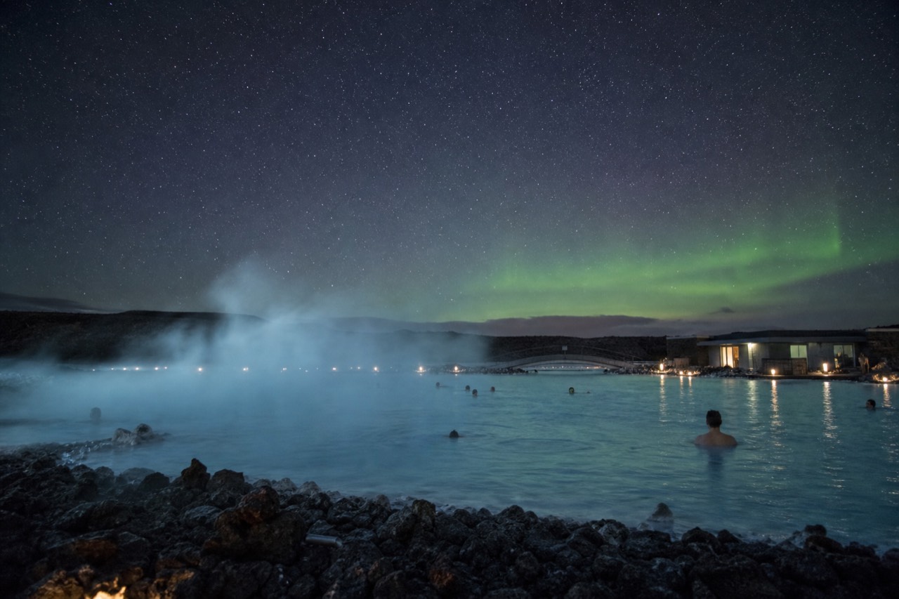 Steam rising from a geothermal lagoon under a dark star-filled winter sky in rural Iceland