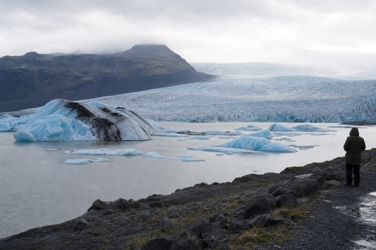 Blue and white icebergs floating on the still grey water of a glacier lagoon