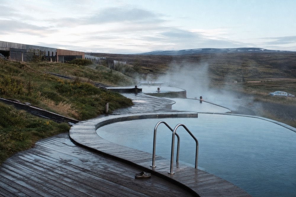 Geothermal pools built into a hillside with steam drifting over still water