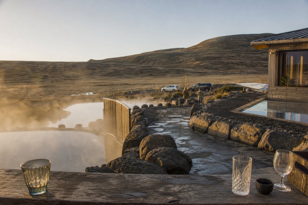A quiet geothermal spa terrace in late afternoon light with low hills behind
