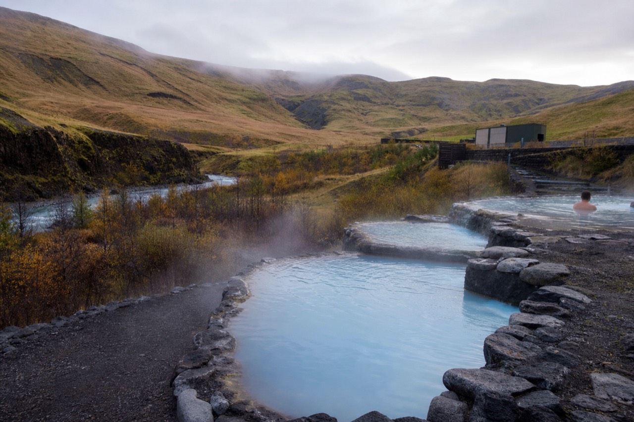 Steaming geothermal lagoon terraces beside a river in rural South Iceland
