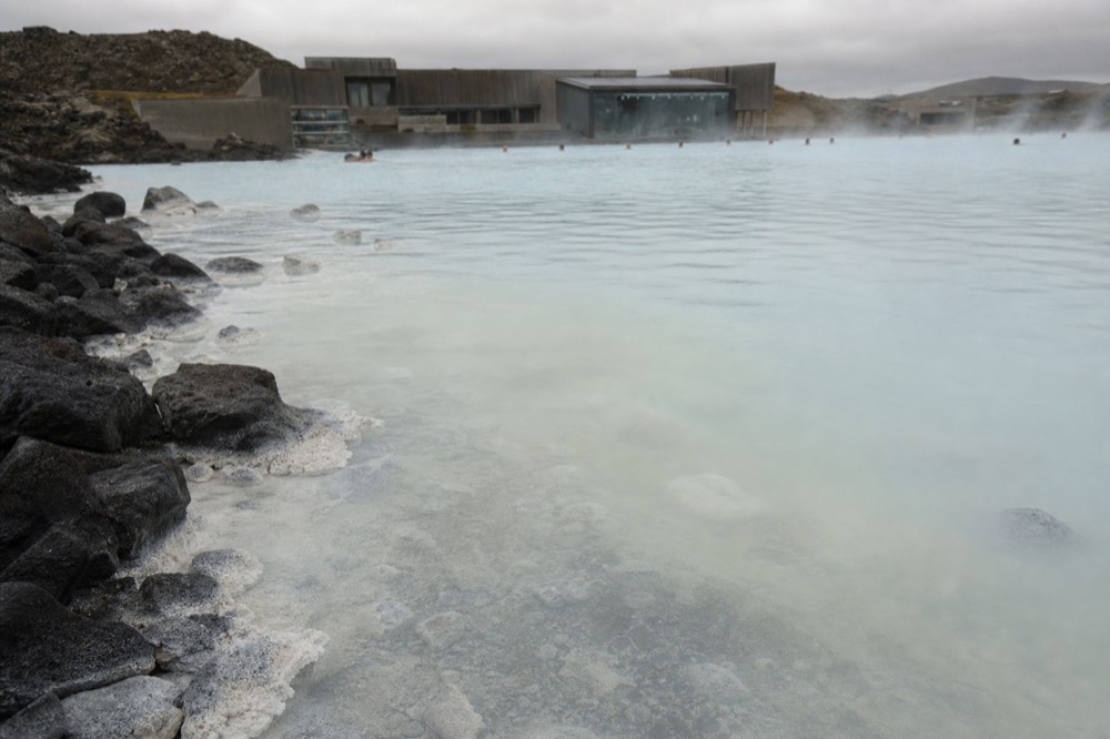 Close view of pale blue geothermal water with mineral deposits along a submerged edge