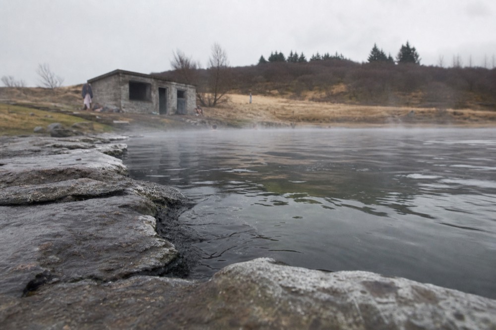 Warm geothermal water in a stone-edged natural pool with steam low over the surface