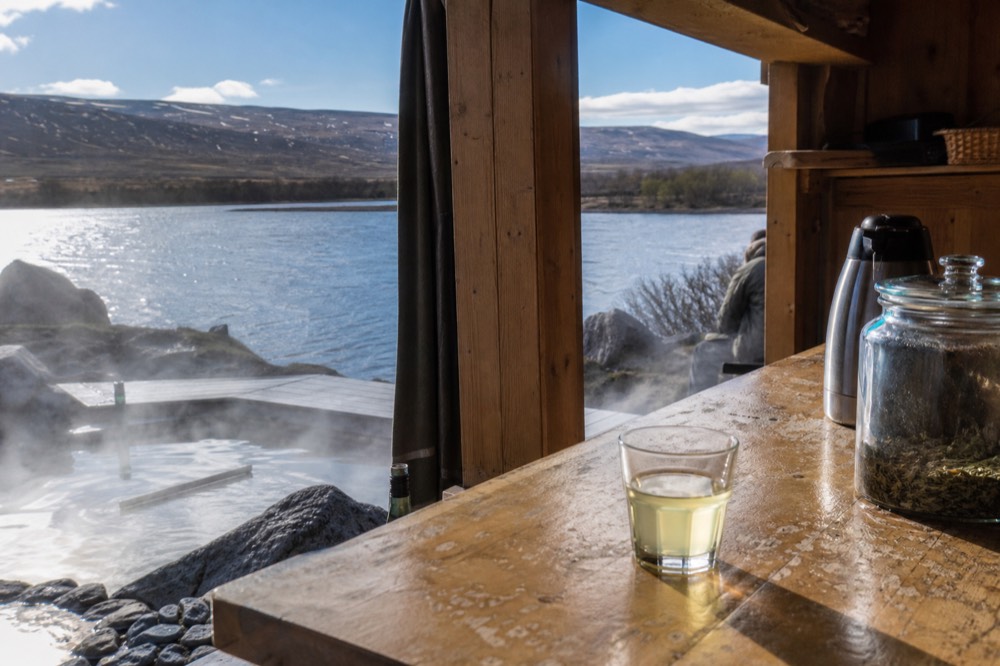 A wooden tea bar beside a steaming geothermal pool