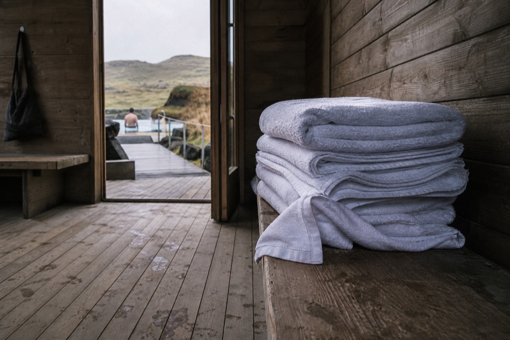 A stack of white towels on a wooden bench in a changing area